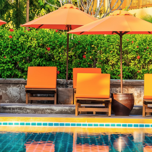 Transats et parasols orange disposés au bord d’une piscine.